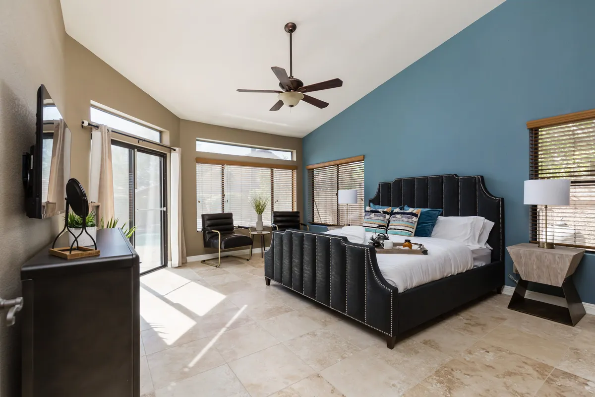 A serene bedroom featuring a bed with decorative pillows, a cozy seating area with chairs, and large windows that bathe the space in natural light. The mood is calm and inviting, ideal for restful nights and tranquil mornings.