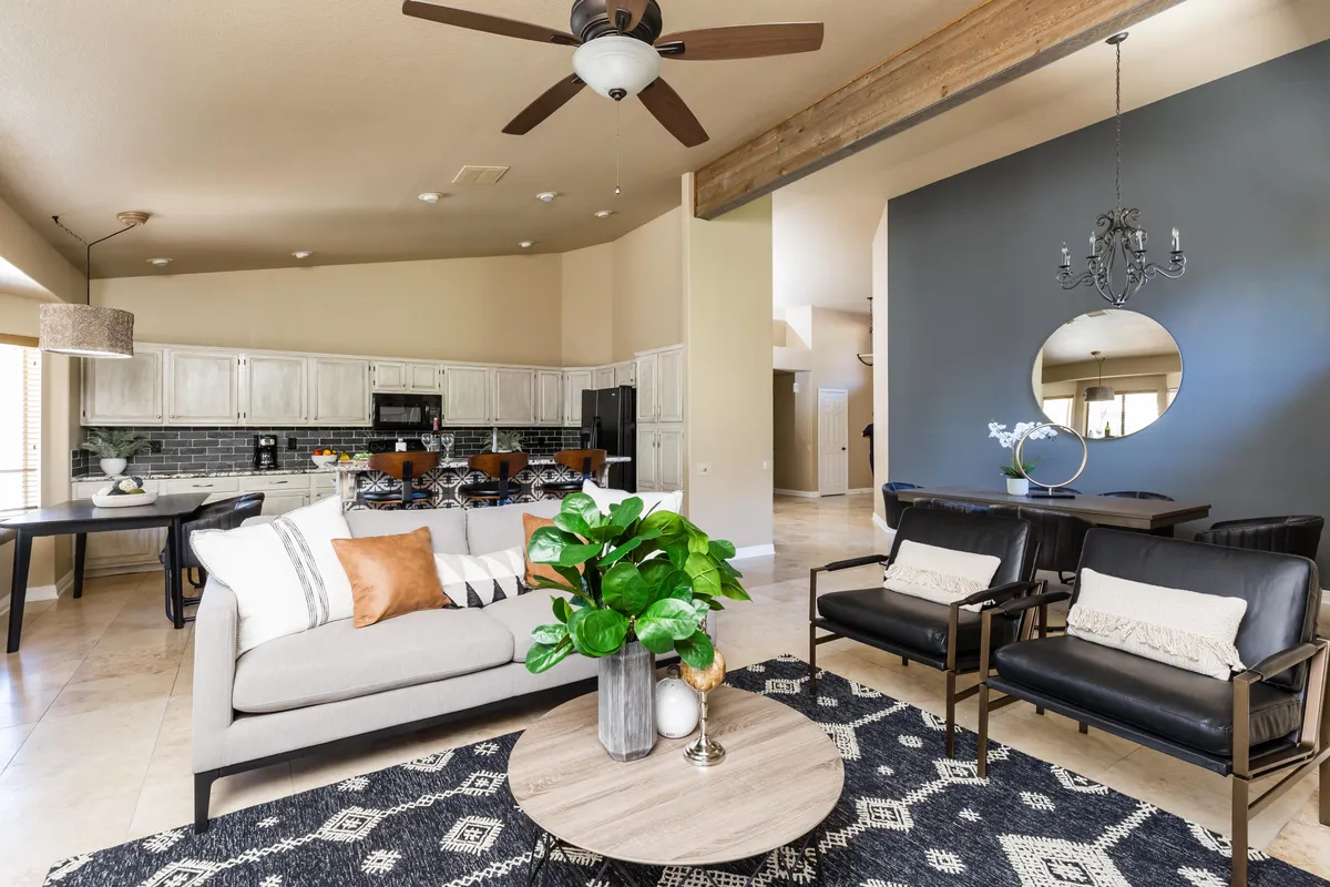 An open-concept living and dining area with a comfortable sofa, coffee table, indoor plants, dining area, and a view into the kitchen. The scene exudes a sense of modern comfort and is ideal for relaxing, entertaining, or gathering with friends and family.