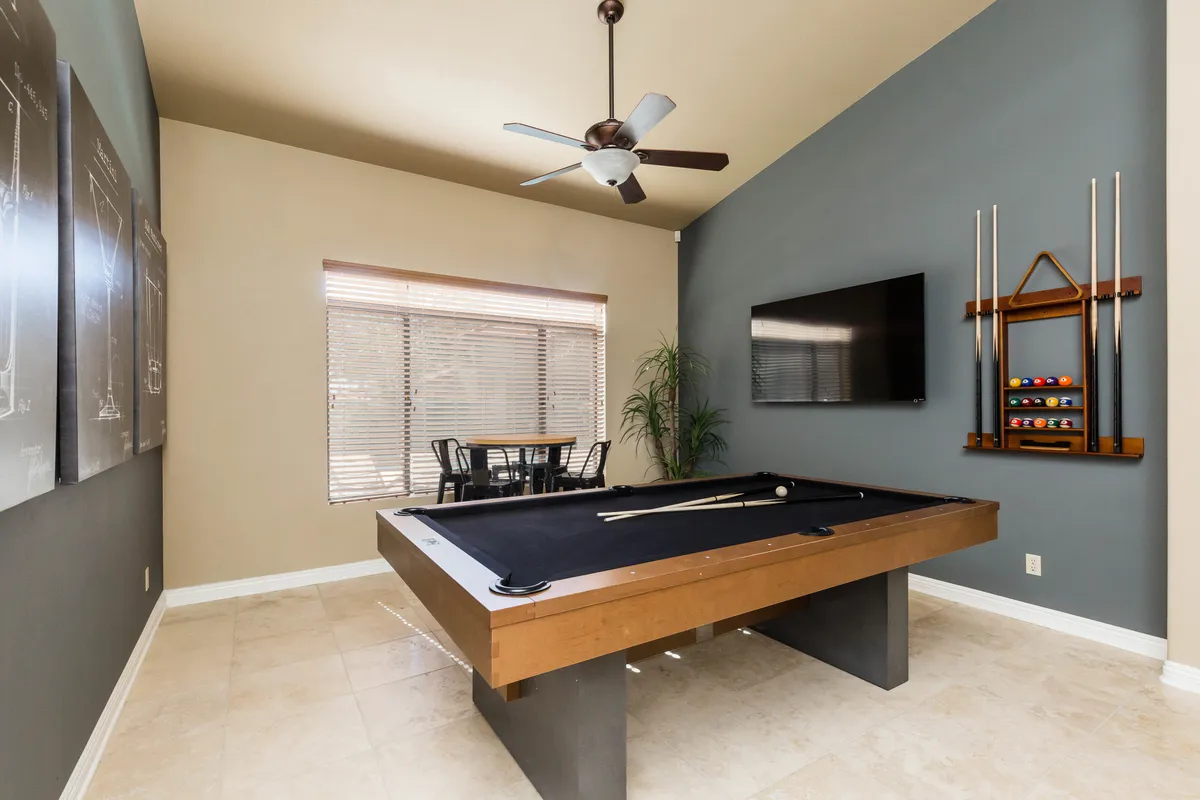 A spacious, well-lit interior featuring a pool table, dining table, wall-mounted television, and contemporary artwork, designed for both social interaction and relaxation. The layout encourages group activities as well as unwinding after meetings.